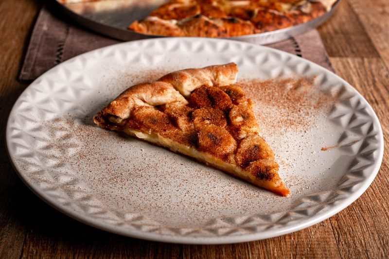 Sweet cinnamon dessert pizza drizzled with icing and brown sugar